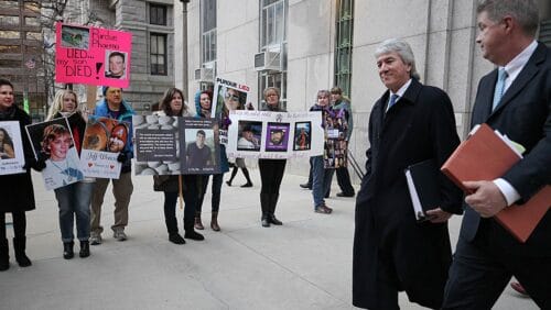 Purdue pharma executives walk past protesting families as they exit a courthouse