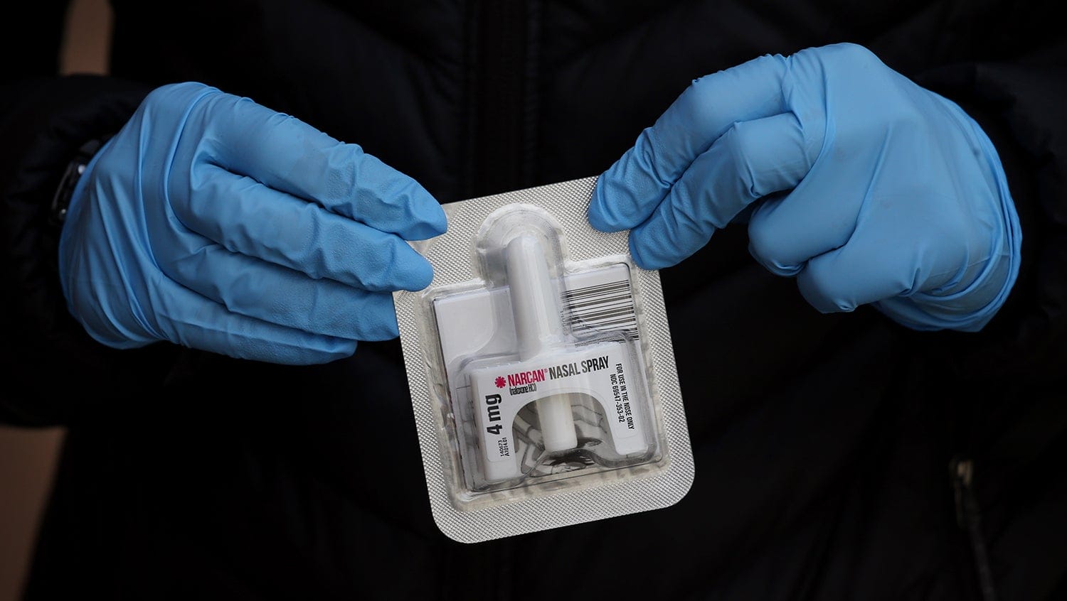 Close up of nurse's blue-gloved hands holding a dose of Narcan (naloxone)