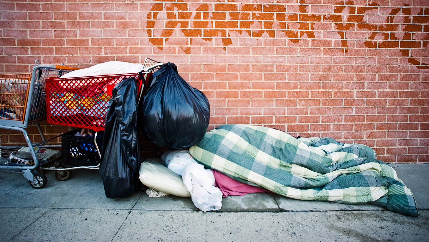 homeless person's belongings and bedding on street sidewalk