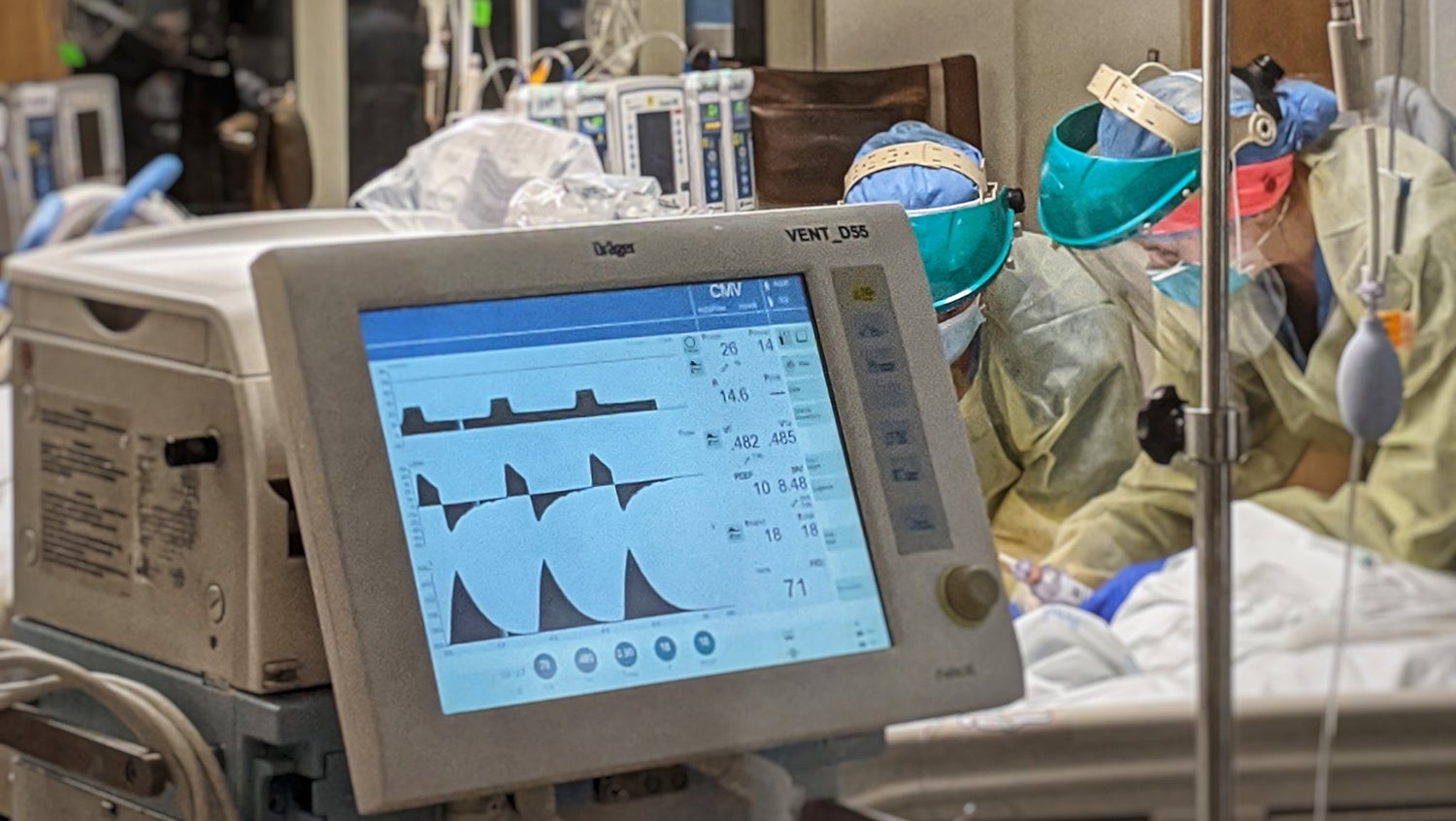 COVID ICU staff work on a ventilated patient on a breathing machine