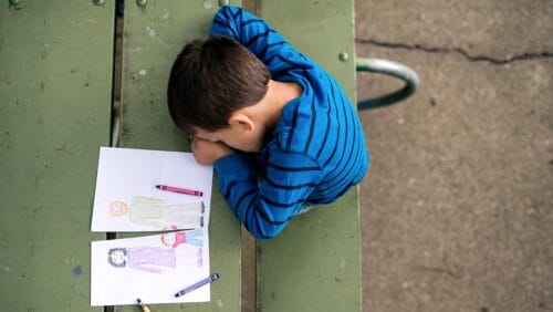 Child experiencing grief draws the loss of a parent with crayons