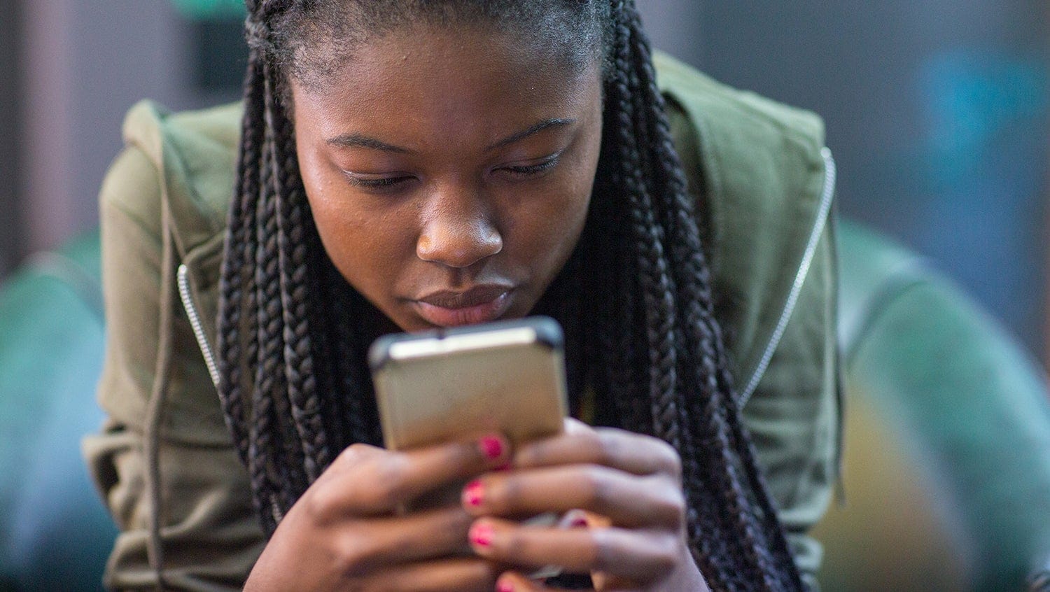 Young black woman stares intently at smartphone screen in her hands