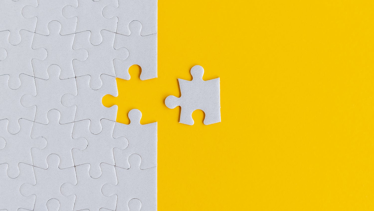 The final puzzle piece sits next to the otherwise completed white puzzle on a yellow background