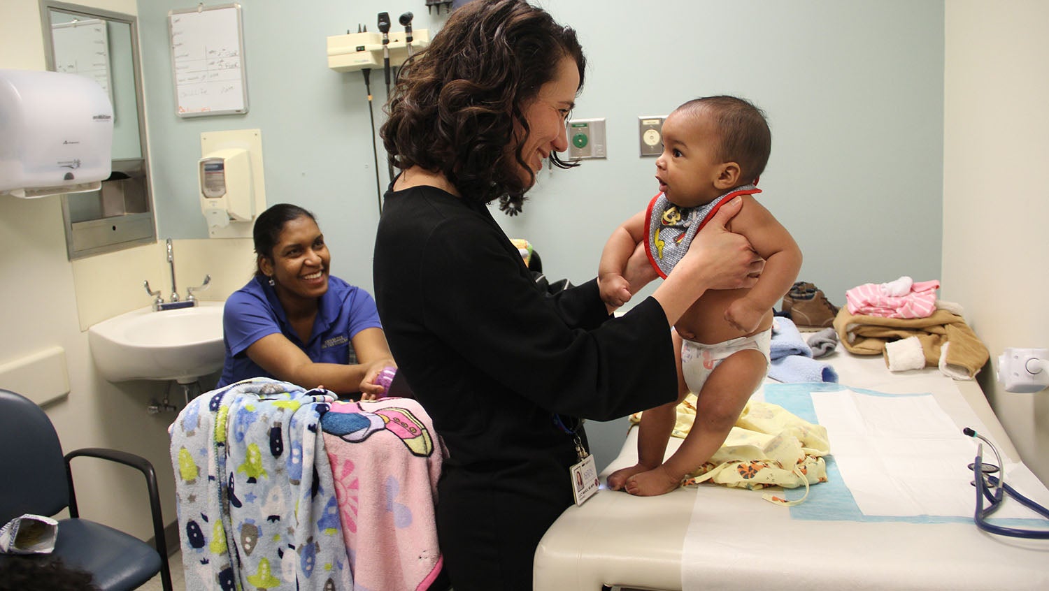 Lucy Marcil, MD holds a baby in a pediatric well visit