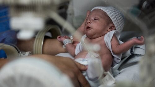 nurse reaching for baby in the NICU 