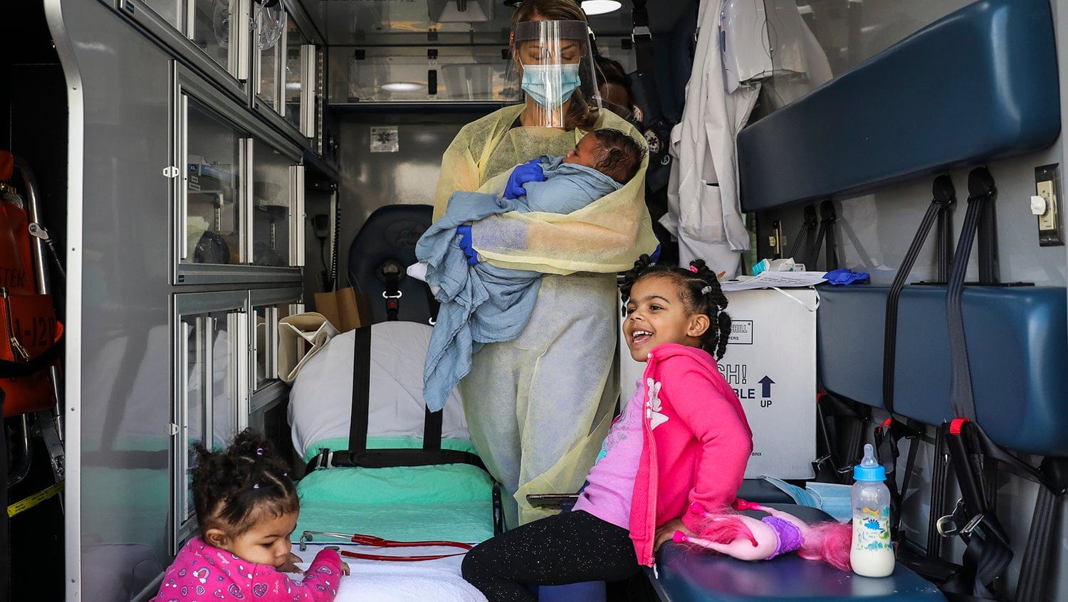 Three young patients smiling inside Boston Medical Center's mobile pediatric clinic.