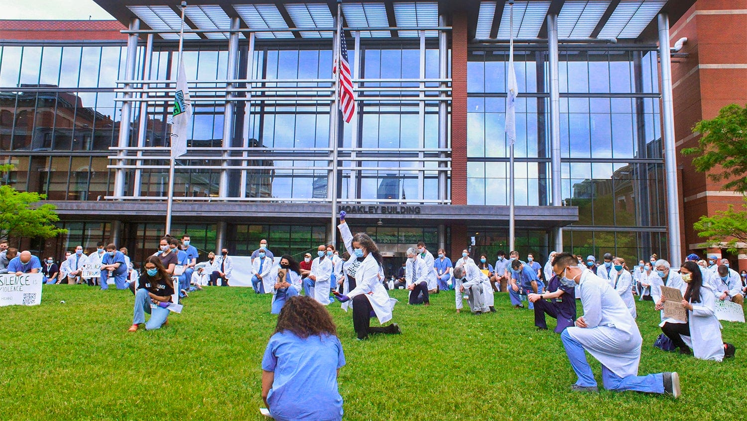 Physicians kneel on the lawn outside Boston Medical Center in a display of solidarity with #WhiteCoatsBlackLives