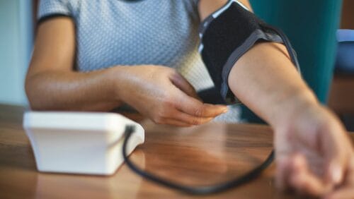 Close-up of woman putting on a blood pressure cuff for postpartum monitoring