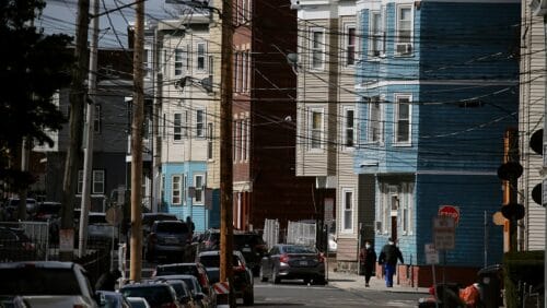 Street view of two people in masks walking in Chelsea Massachusetts which is a community hard hit by coronavirus as a result of racial inequities.