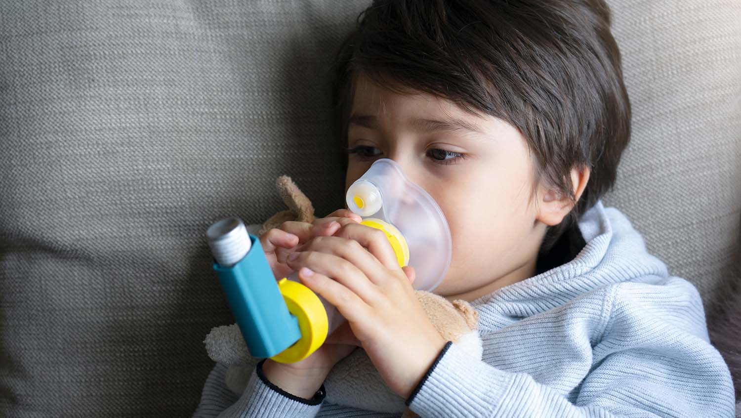 A boy uses an asthma inhaler with a spacer