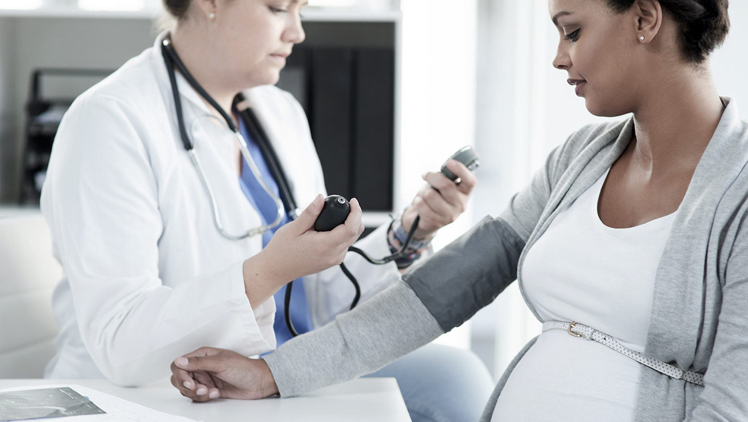 doctor checks blood pressure of pregnant patient