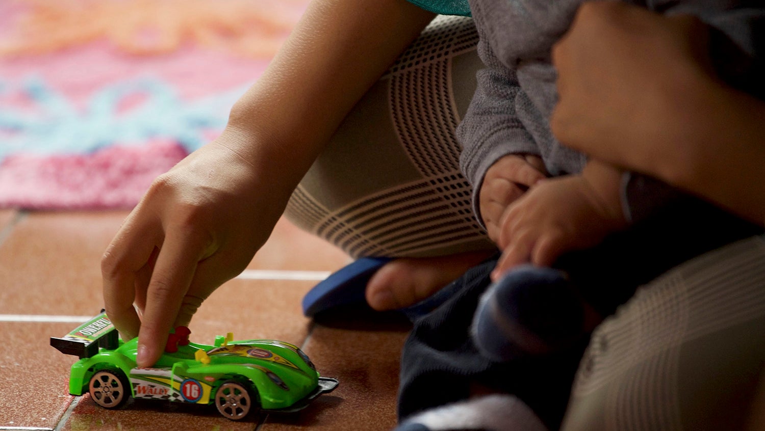 new mother with baby on her lap playing with a car toy
