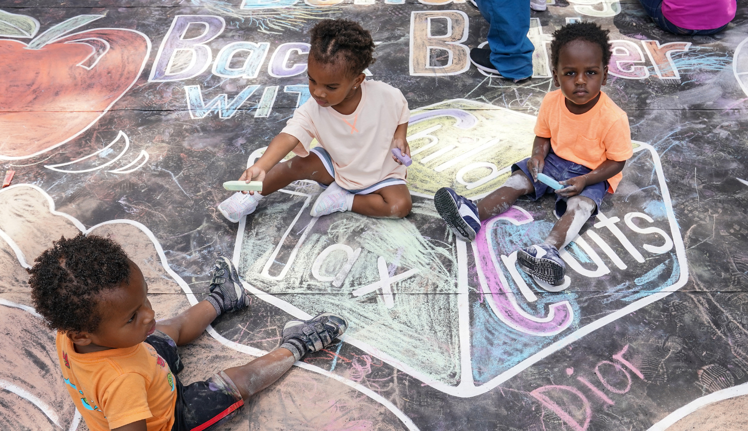 Three children with child tax credit chalk art on the pavement
