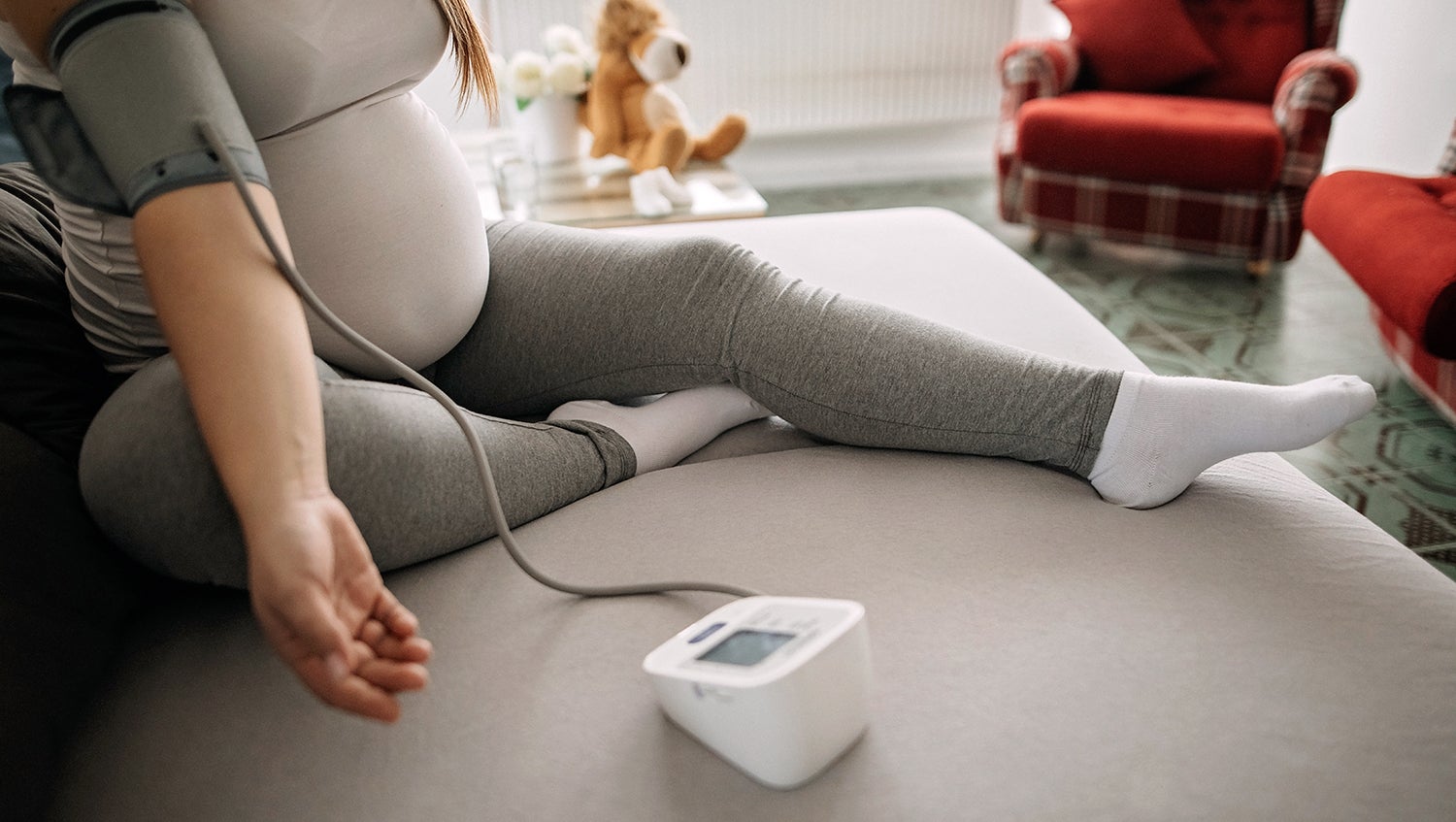 pregnant woman monitoring blood pressure remote at home
