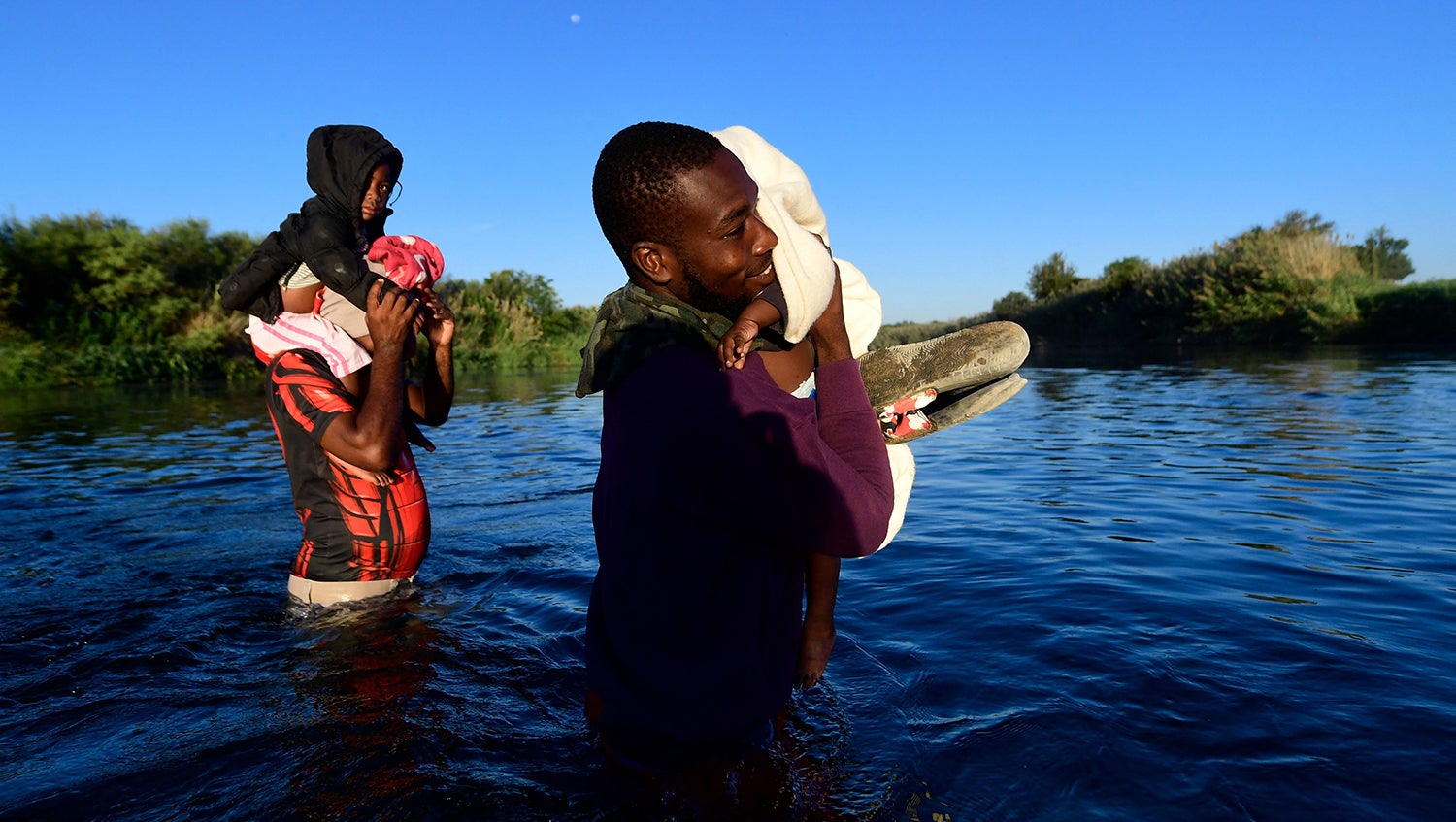 family of haitian migrants cross the Rio Grande holding children