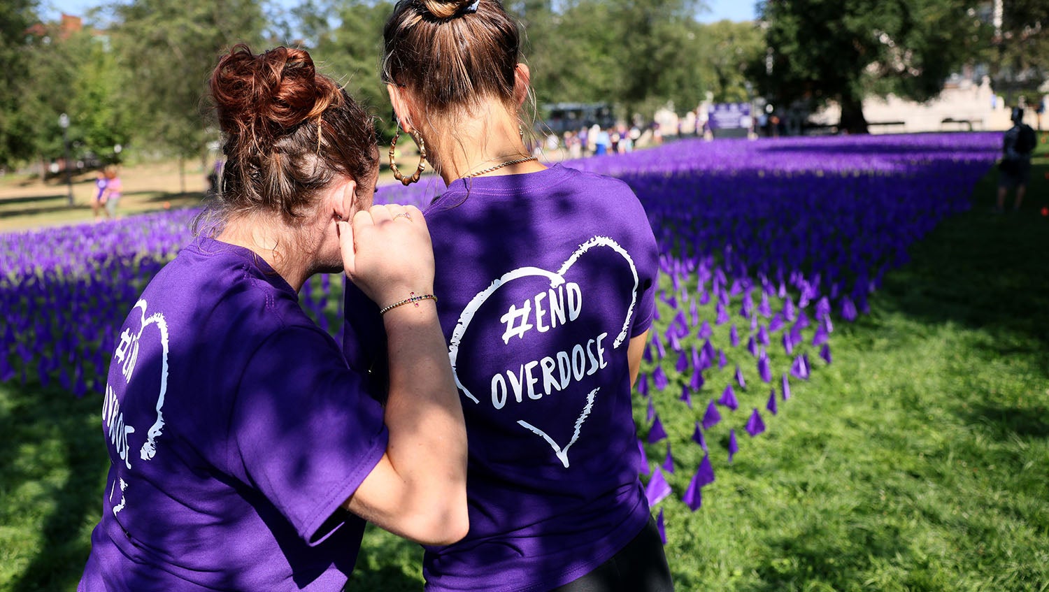 two people hugging at overdose awareness day event wearing purple