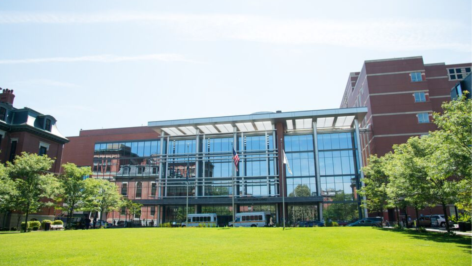 a photo of the boston medical center moakley green. it is a bright sunny day and blue skies are reflecting off of the windows.