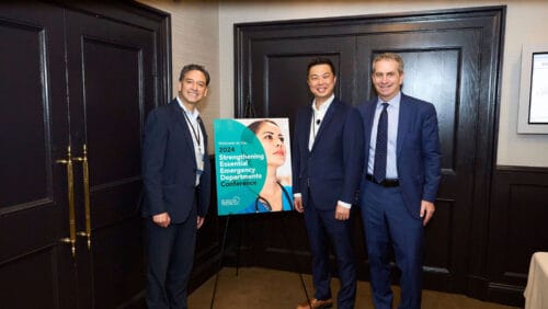 david yun and christian arbalez of boston medical center pose in front of sign for Strengthening Essential Emergency Departments conference.