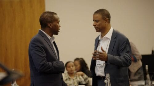 (L to R) Bonga Chiliza, MBChB, FCPsych, PhD greets David Henderson, MD in a recent video about AGMHI (Boston Medical Center). 