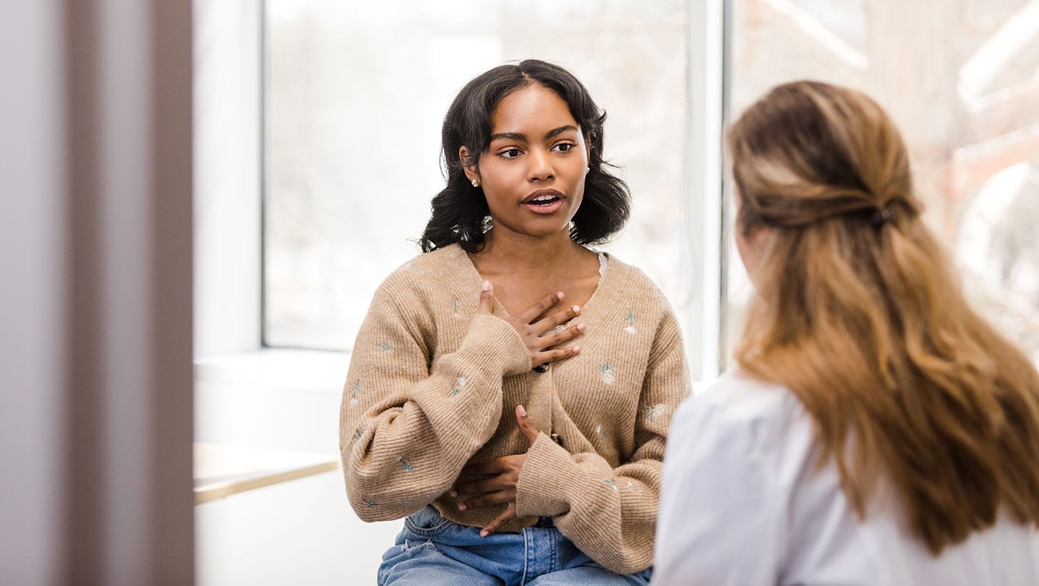 young black woman sitting in a doctor's office and speaking to an unseen doctor