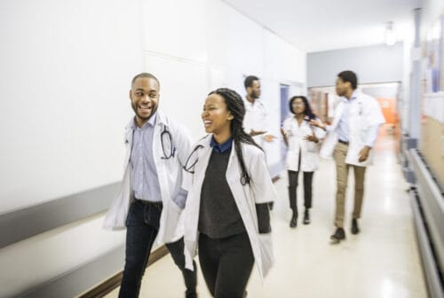 a team of diverse doctors in white coats walking down a hallway