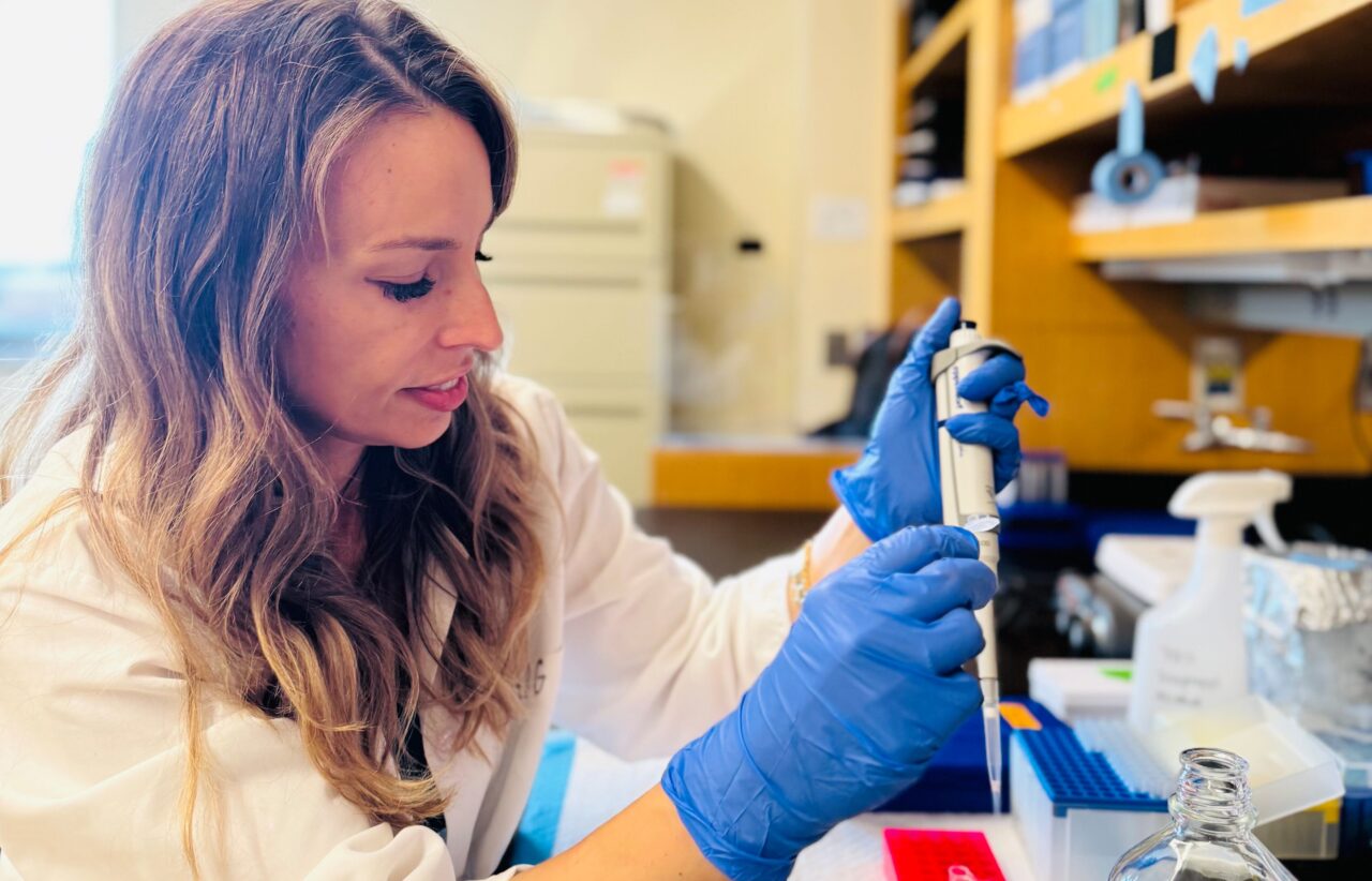 elizabeth taglauer, a young woman with wavy blond hair, wearing blue medical gloves working in a research lab