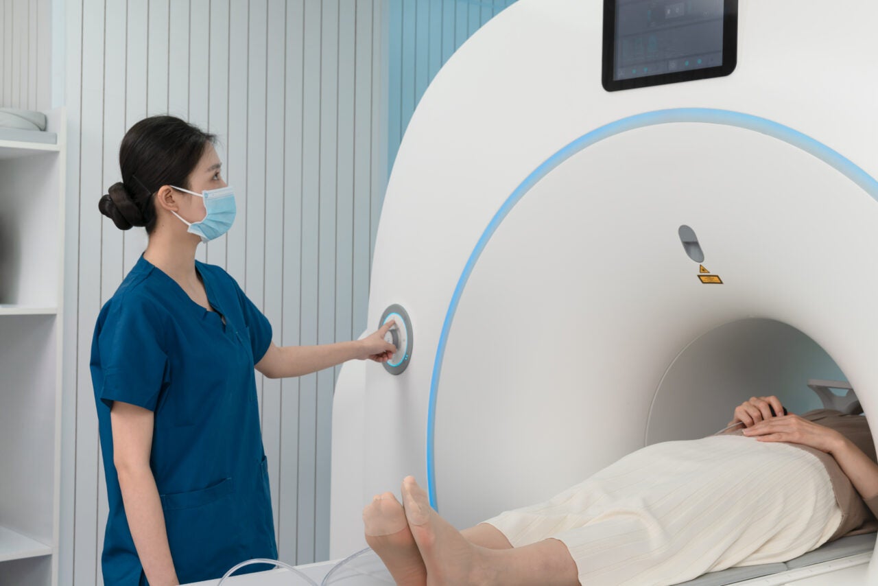 A nurse prepares an older woman patient for hospital MRI scan at hospital