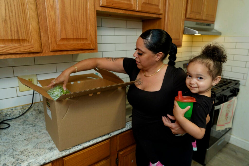 April Martinez of Dorchester, Massachusetts unpacks a food box in her kitchen alongside her youngest daughter.
