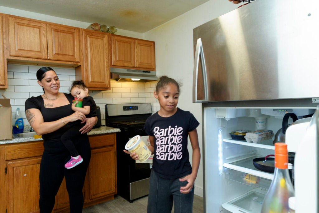 April Martinez unpacks the contents of the food box in her kitchen with her two children.