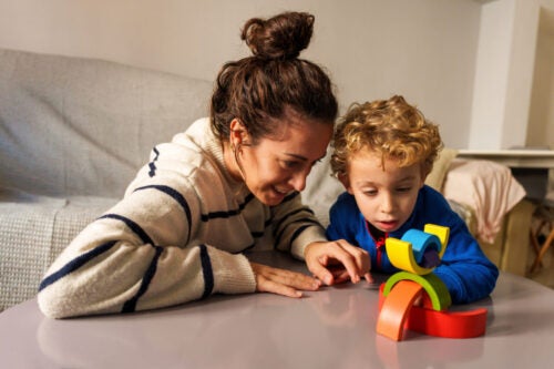 Mother and son playing with a wooden stacking toy on a table. Learning and development through creative play at home