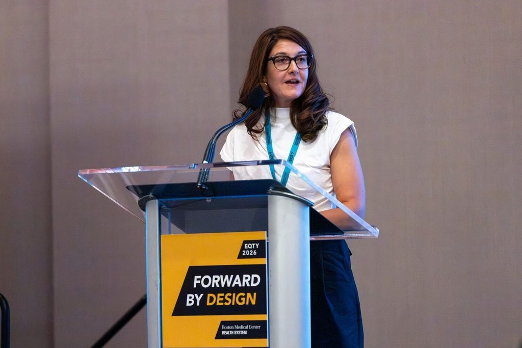 Johanna Chesley at the Inclusive Research Symposium speaking behind a translucent podium